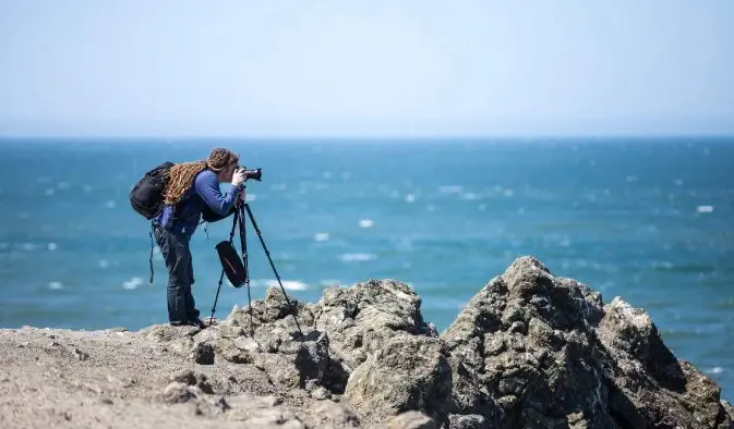 Il fotografo Laurence Norah e la sua attrezzatura si sono sistemati vicino all'oceano per scattare foto