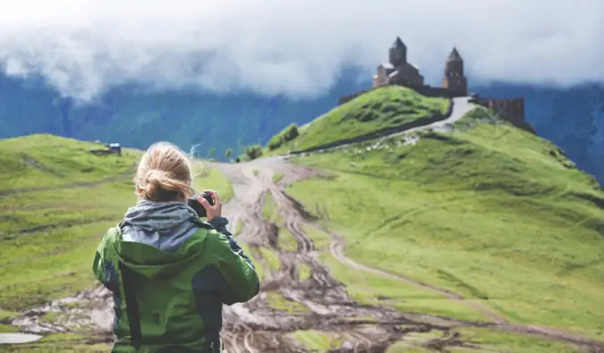 Samostatný cestovatel fotografující hrad na kopci