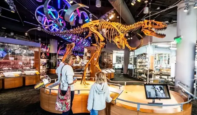 Seorang ibu dan anak perempuan berdiri di hadapan rangka dinosaur di Muzium Sains Semula Jadi di Raleigh, Carolina Utara