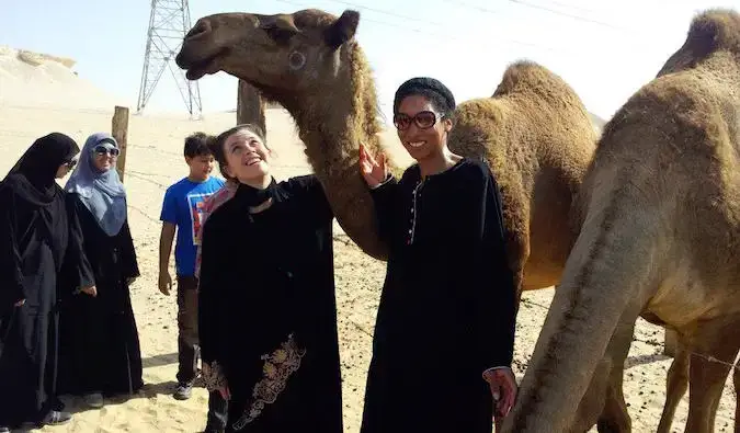 Mulher ensinando na Arábia Saudita em uma fazenda de camelos vestindo roupas do Oriente Médio