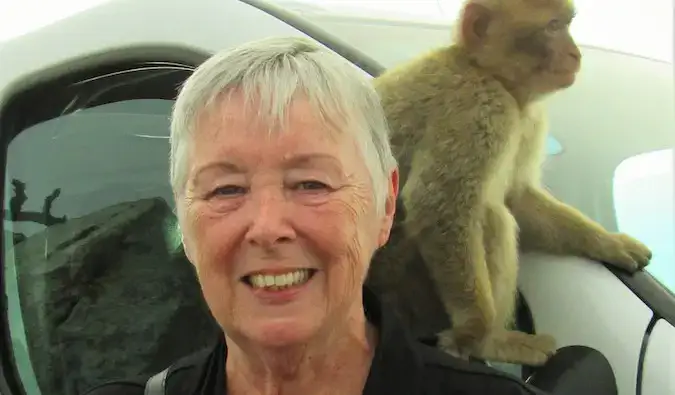 Senior reiziger Sherrill met een aap op haar schouder op reis naar het buitenland