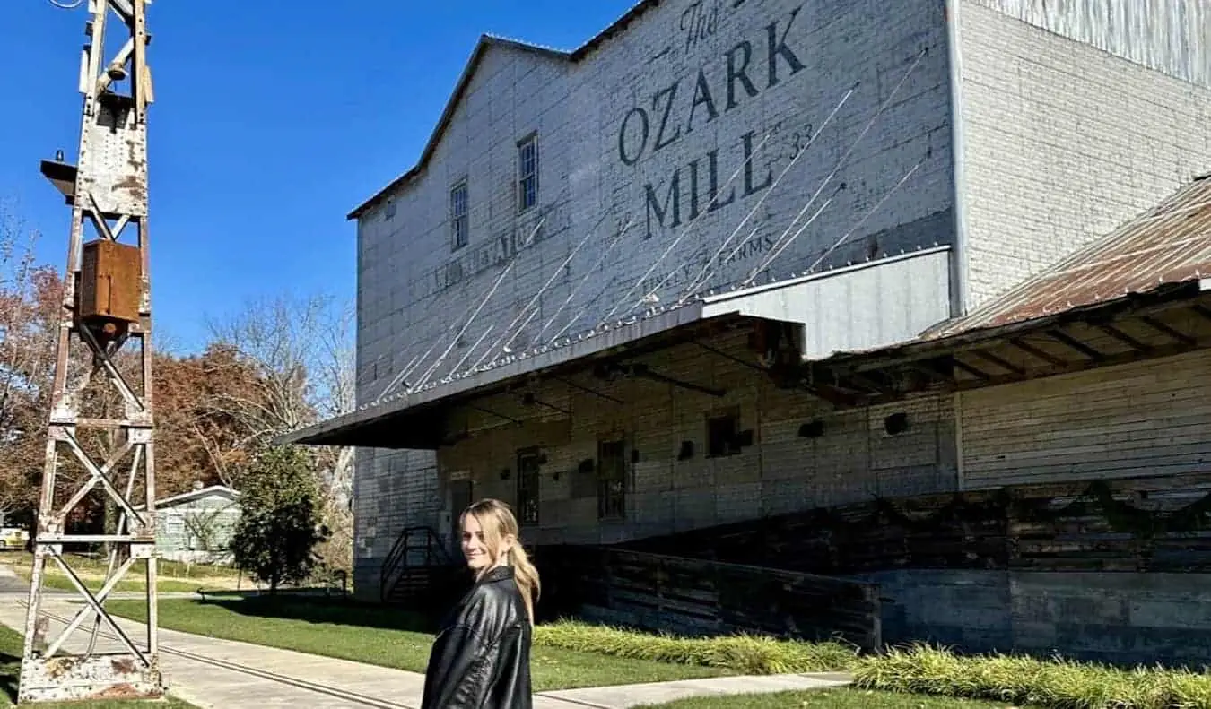 Bloger podróżniczy Raimee Iacofano pozuje w pobliżu starego budynku gospodarczego podczas wycieczki Route 66 w Missouri