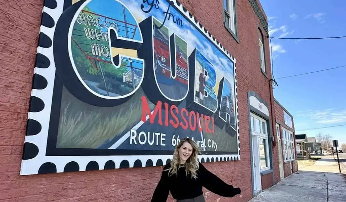 Reisblogger Raimee Iacofano poseert bij een muurschildering in Cuba, MO tijdens een Route 66-roadtrip