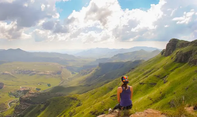 Alleinreisende Kristin Addis sitzt auf einem Berggipfel und blickt auf die Aussicht