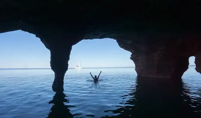 O călătoare singură înotând lângă caverne oceanice