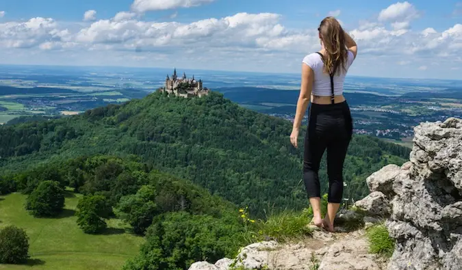 Nakatingin si Kristin sa isang magandang kastilyo sa di kalayuan sa ibabaw ng isang luntiang burol sa Europa