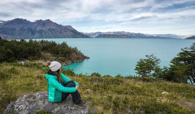 Una donna che viaggia da sola in posa su un molo vicino alle montagne