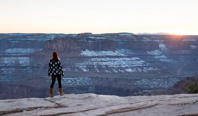 Kristin Addis seisoo Grand Canyonin edessä kevyen lumen kanssa