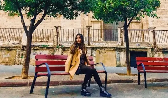 Natasha, uma viajante solitária e professora de inglês na Espanha, sentada em um banco