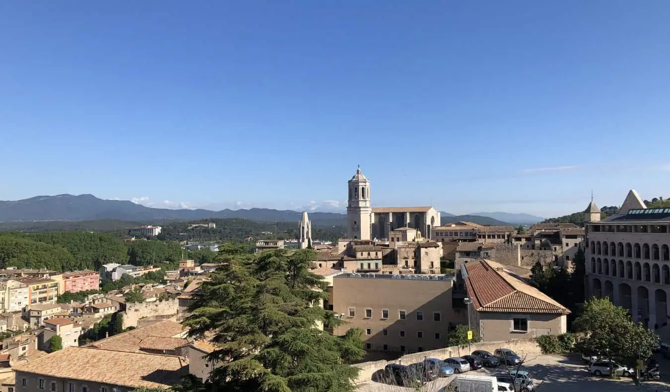 Pemandangan atap terakota, dengan latar belakang katedral dan pegunungan, di Girona, Spanyol