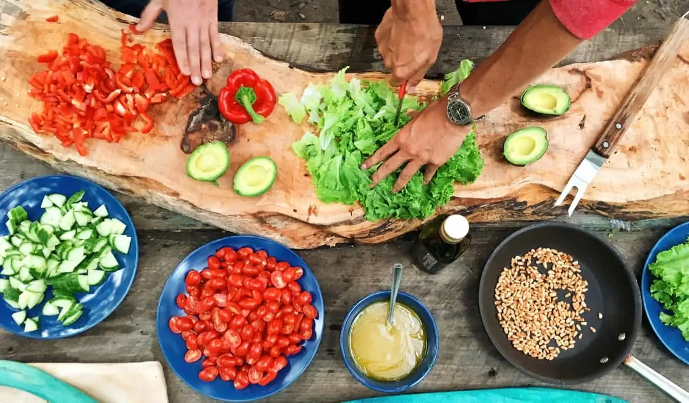 Zwei Personen kochen auf einer Küchentheke ein exotisches, farbenfrohes Gericht