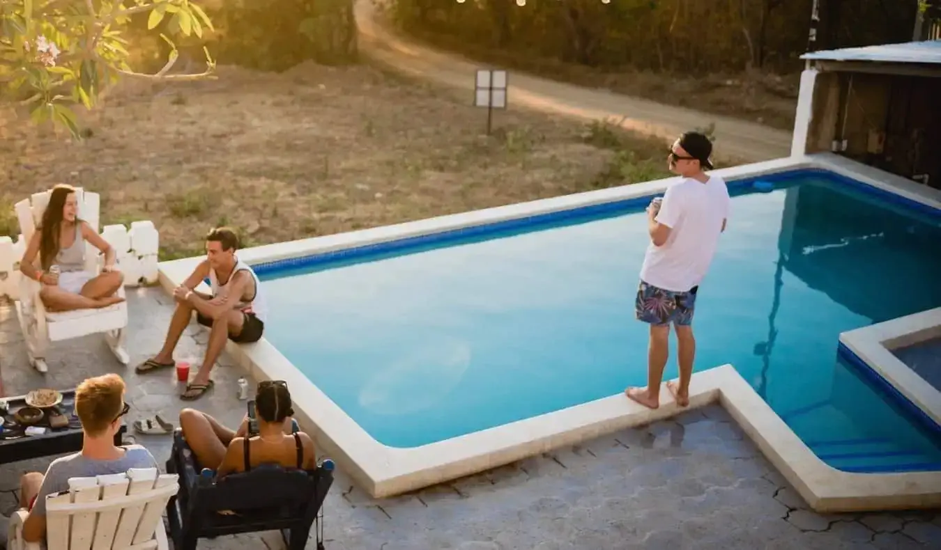 Eine Gruppe von Reisenden hängt am Pool eines Hostels im Ausland ab