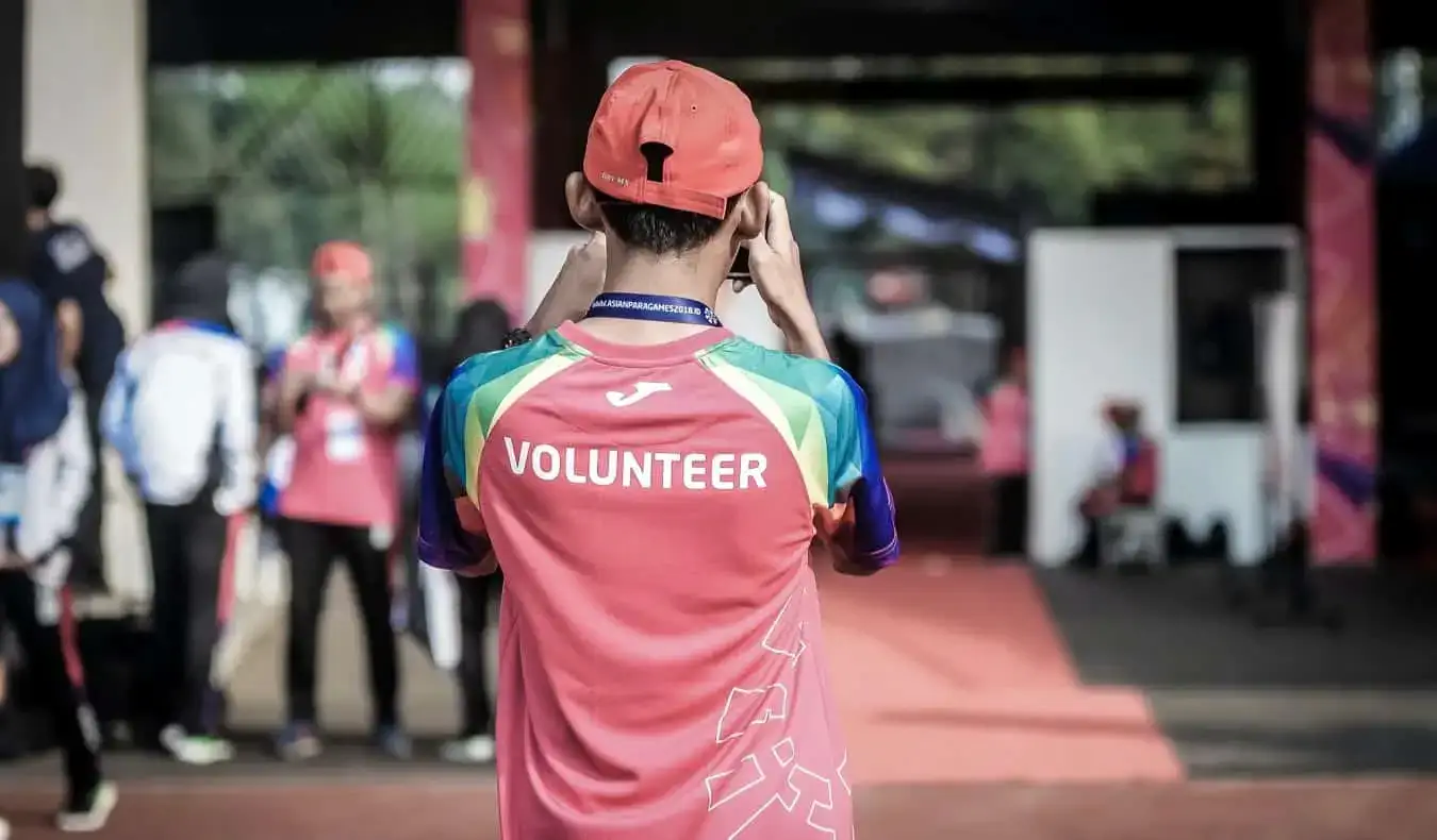 Seorang pria muda menjadi sukarelawan di acara publik besar selama musim panas