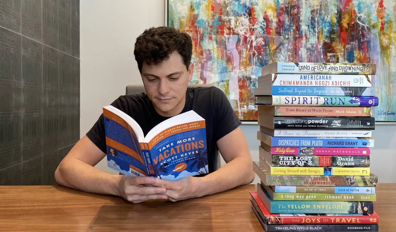 Nomadic Matt lendo um livro de viagens em uma mesa