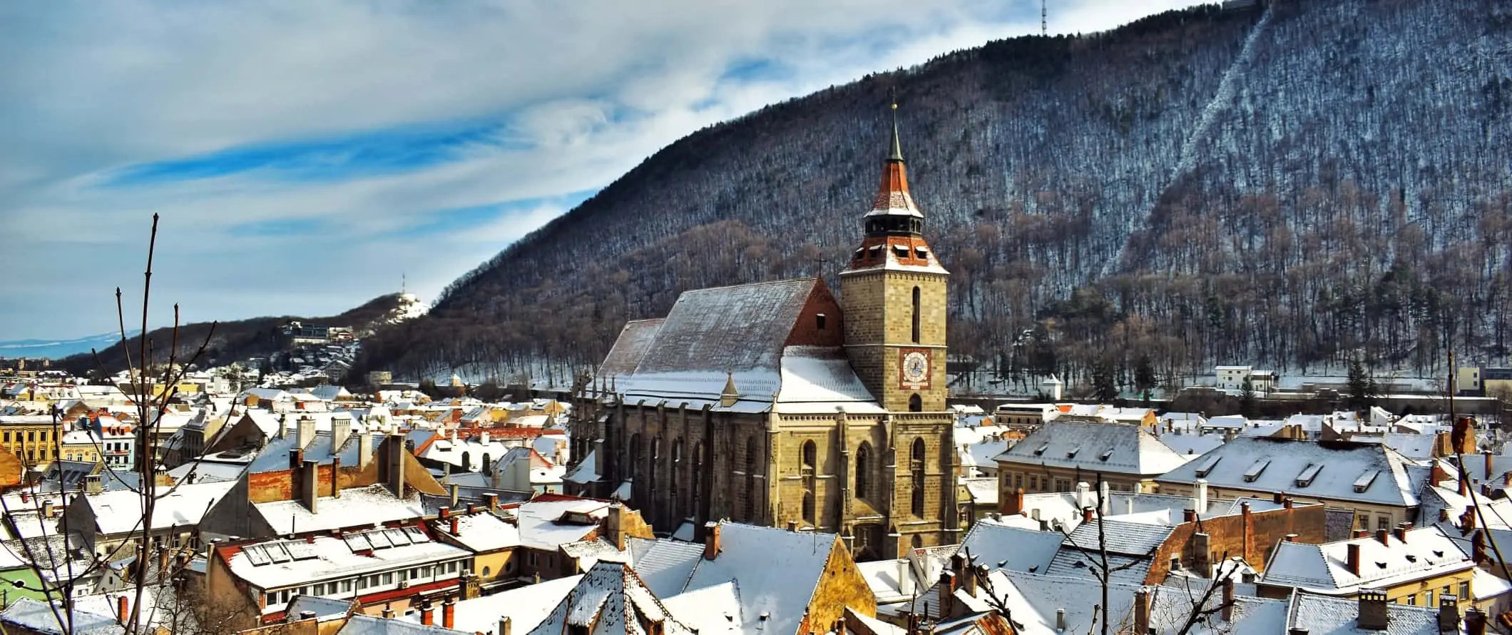 Den svarte kirken fra 1300-tallet ruver over snødekte bygninger i Brasov, Romania.