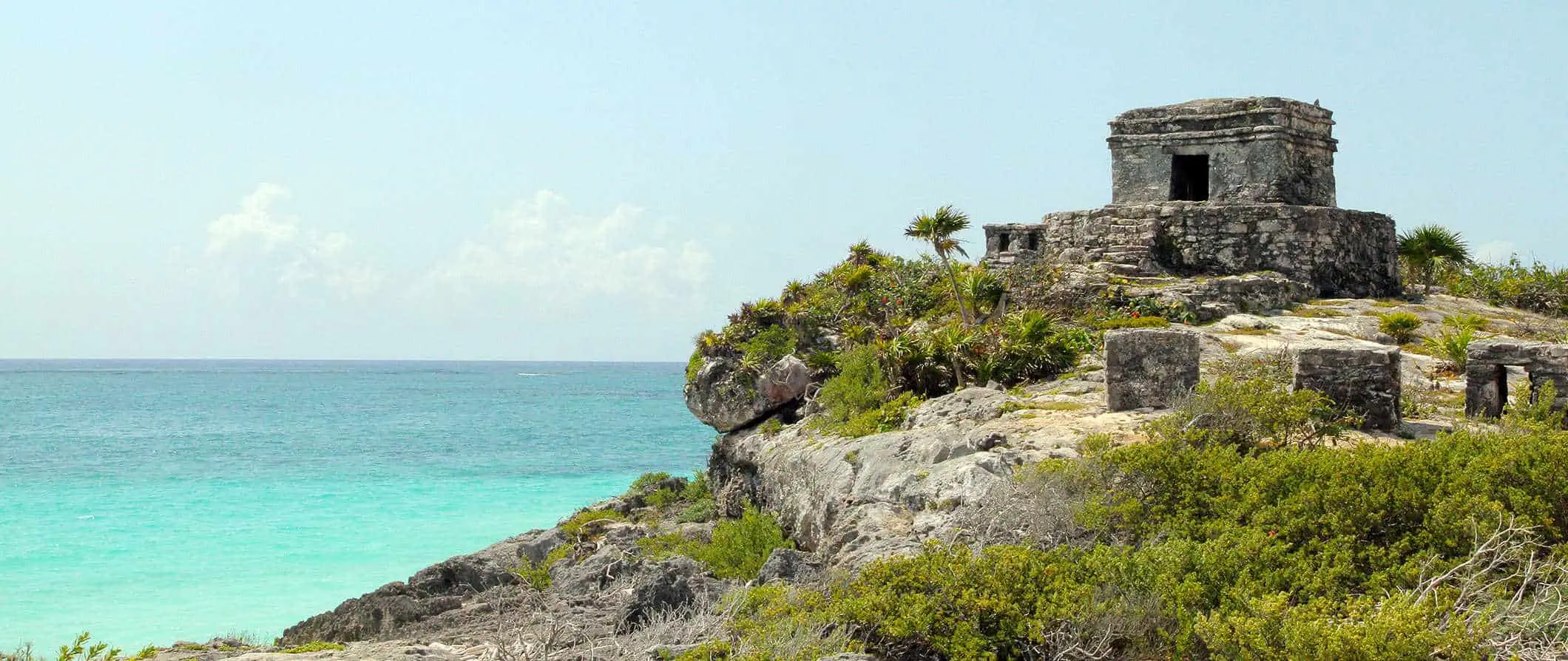 Makasaysayang mga guho malapit sa karagatan sa Tulum, Mexico na may malago na halaman sa isang maaraw na araw