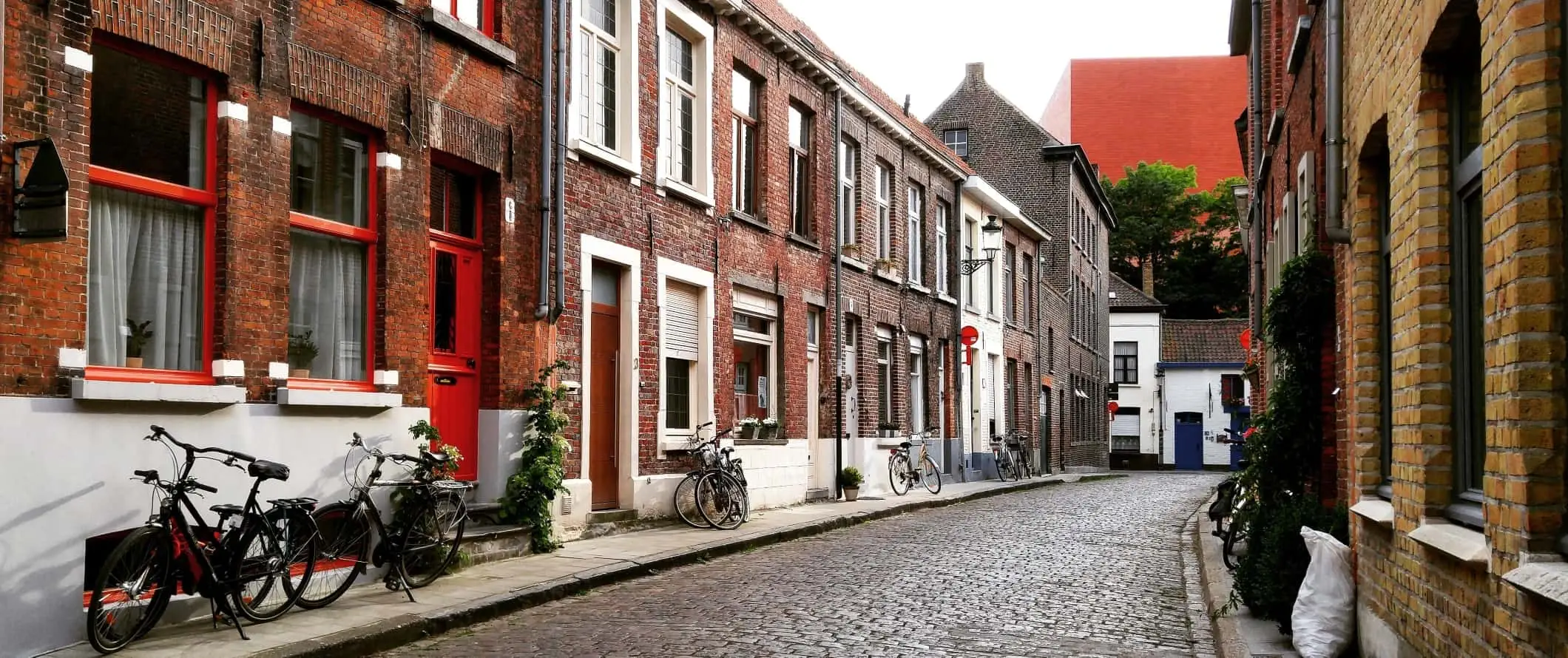 Brostensbelagt gade med cykler parkeret langs siden af ​​vejen i Brugge, Belgien.