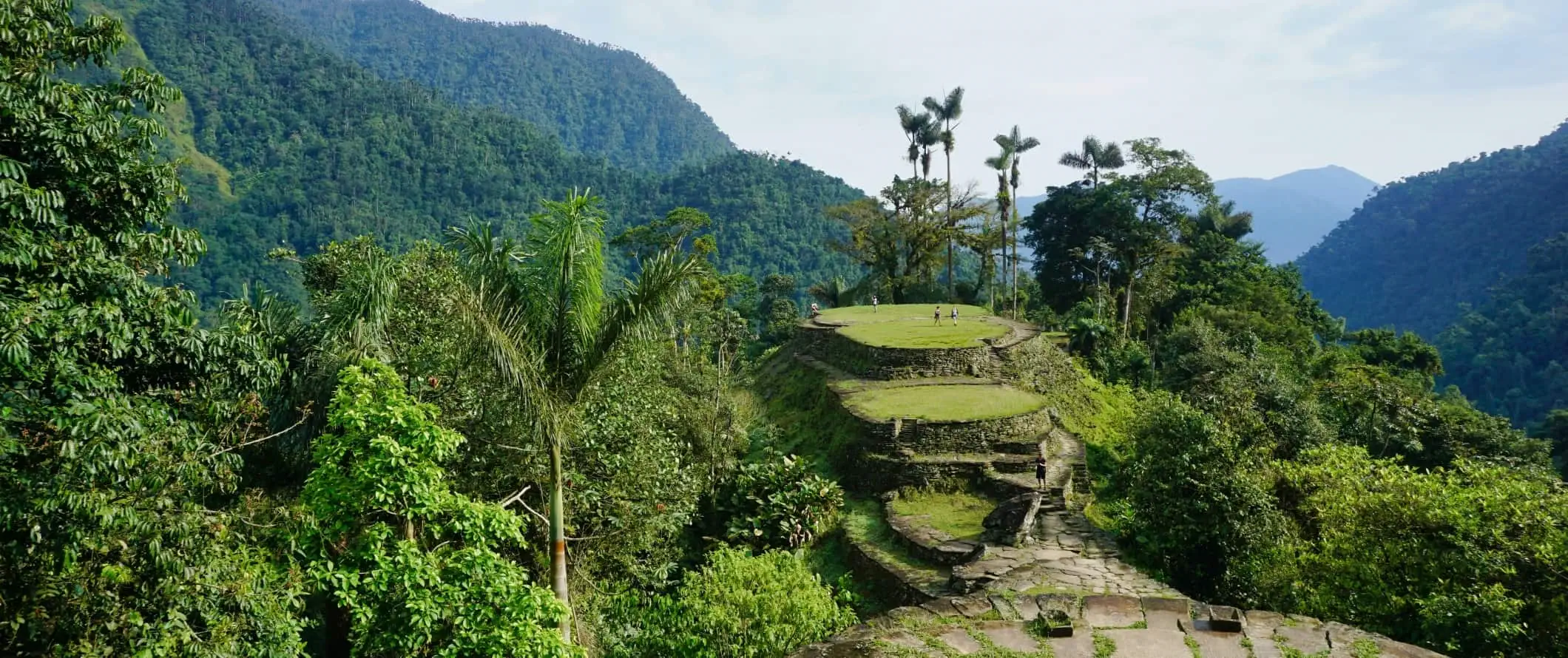 Folk går rundt på ruinerne Ciudad Perdida i regnskoven i Colombia