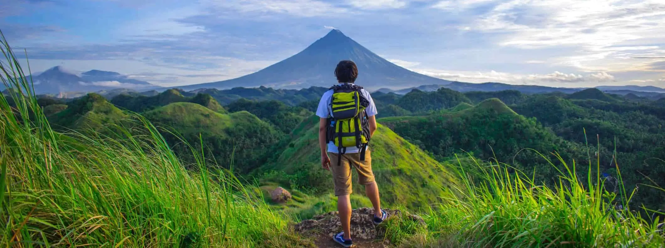 Isang solong manlalakbay na nag-pose malapit sa isang bundok habang naglalakbay sa ibang bansa