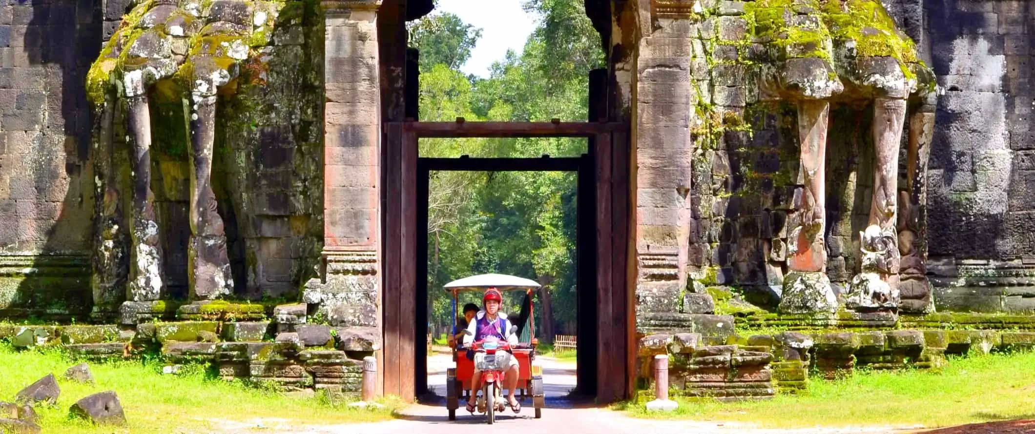 Tuk tuk áthalad a kambodzsai Angkor Wat történelmi templomegyüttesének nagy, bonyolultan faragott bejáratán