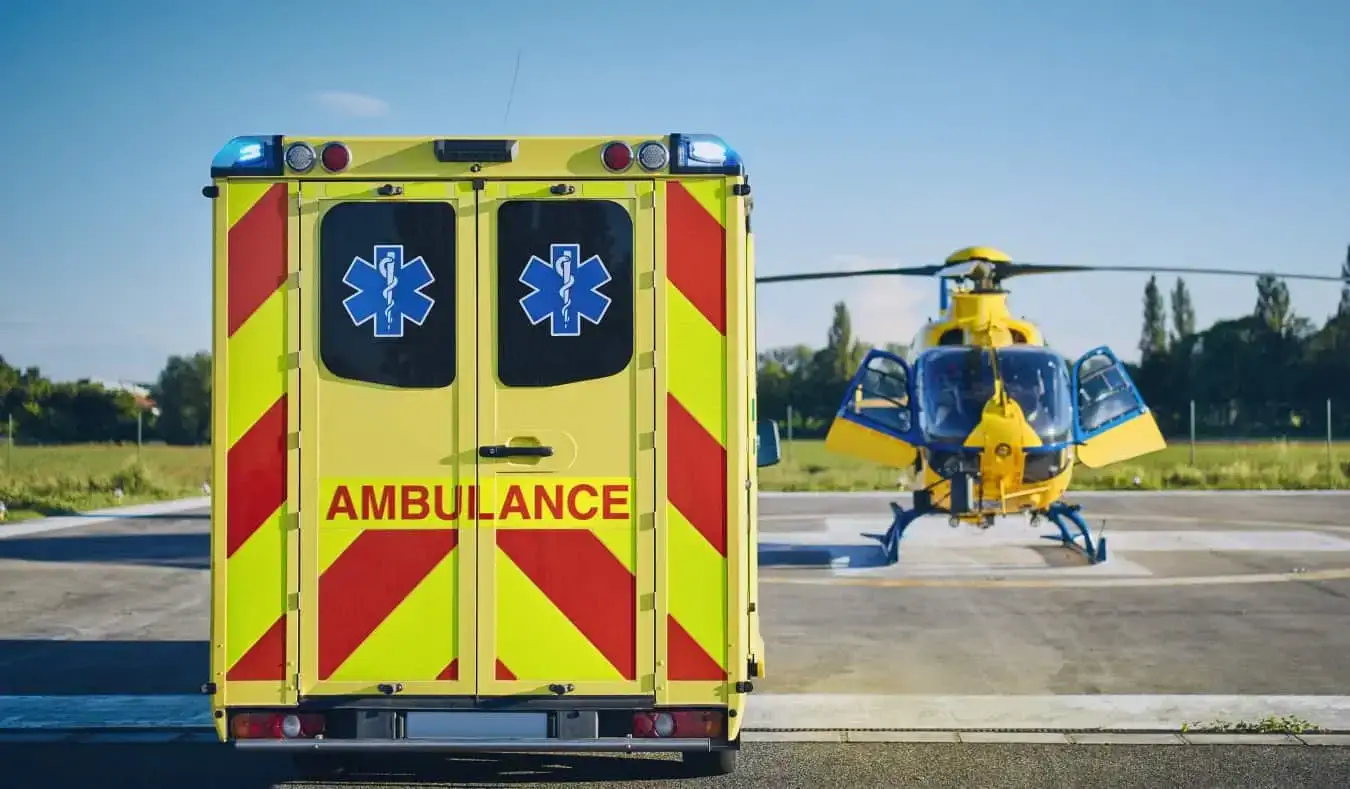 Acil durum helikopterinin yanına park edilmiş sarı bir ambulans