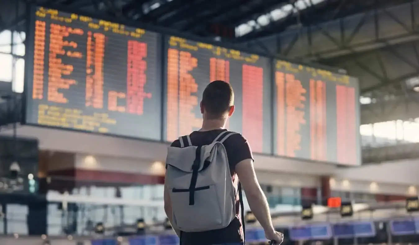 Een man die zich voordeed op een luchthaven in de buurt van een groot bord