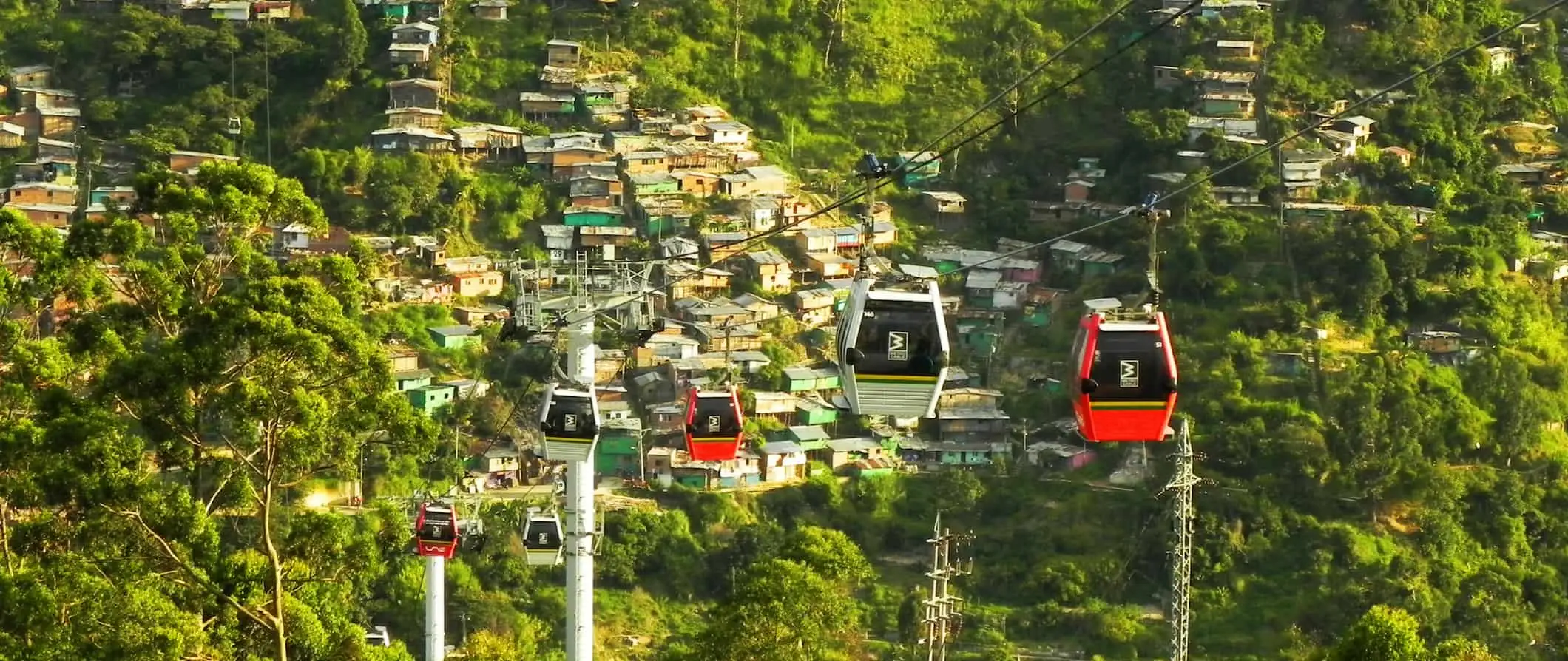 A városra néző kilátás a kolumbiai Medellín felvonóira buja növényzettel és a hegyoldalba épített kis házakkal körülvéve