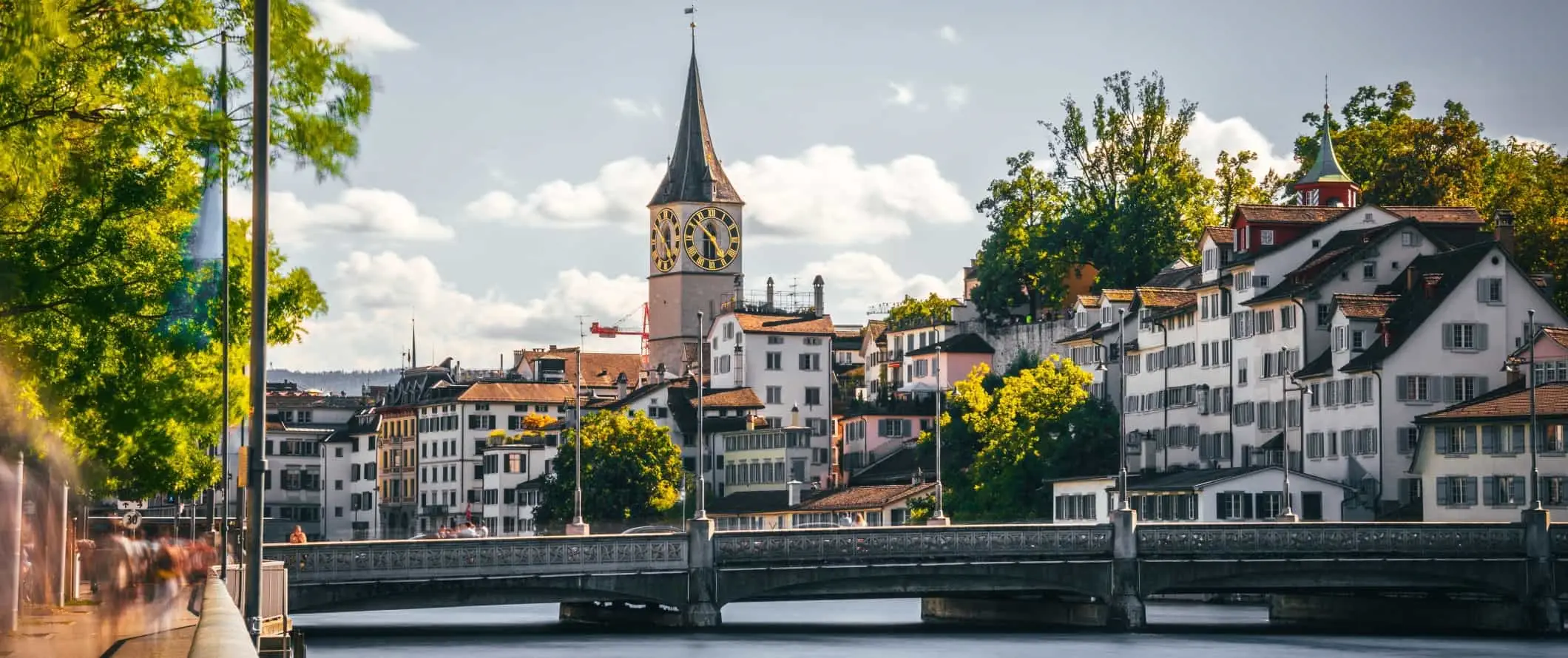 Edifícios históricos à beira-mar e uma grande torre de relógio histórica no centro da Cidade Velha de Zurique, Suíça