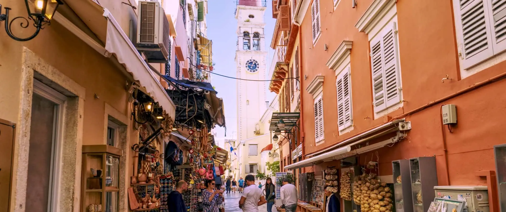 Vue d'un clocher au bout des rues étroites et animées de la ville de Corfou, en Grèce.