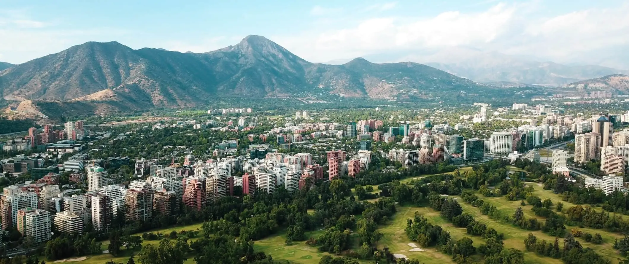 De stad Santiago ligt in een vallei met bergen die oprijzen achter de hoge gebouwen in Chili