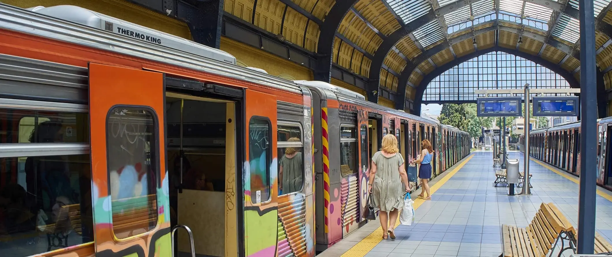 Heller, von Tageslicht durchfluteter Bahnhof in Athen mit einem farbenfrohen U-Bahn-Wagen.