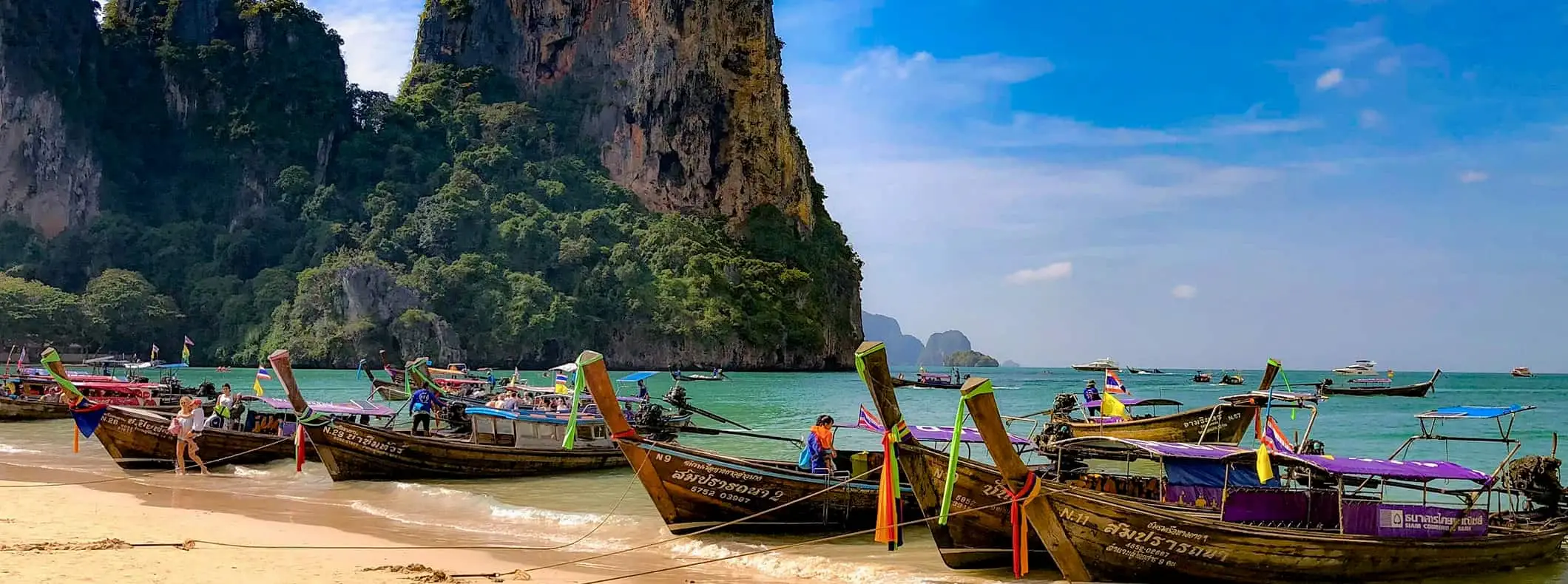 Una fila de embarcaciones de cola larga estacionadas en una impresionante playa de Tailandia