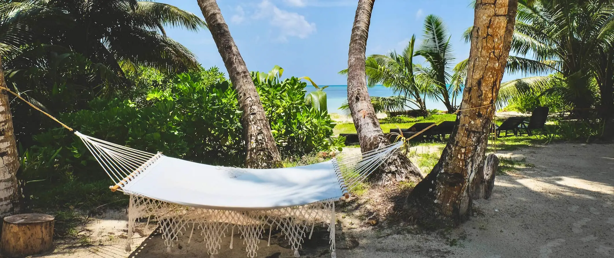 Ein tropischer Strand mit einer Hängematte auf den Seychellen mit weißem Sand und einem strahlend blauen Himmel darüber