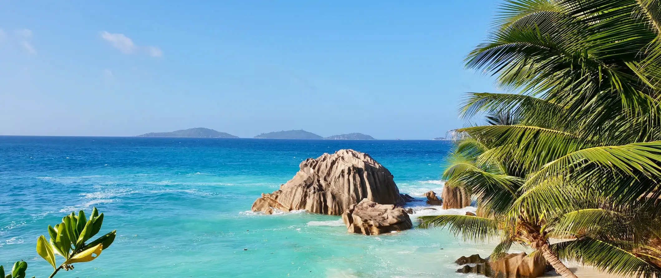 Een tropisch strand op de Seychellen met wit zand en een helderblauwe lucht erboven