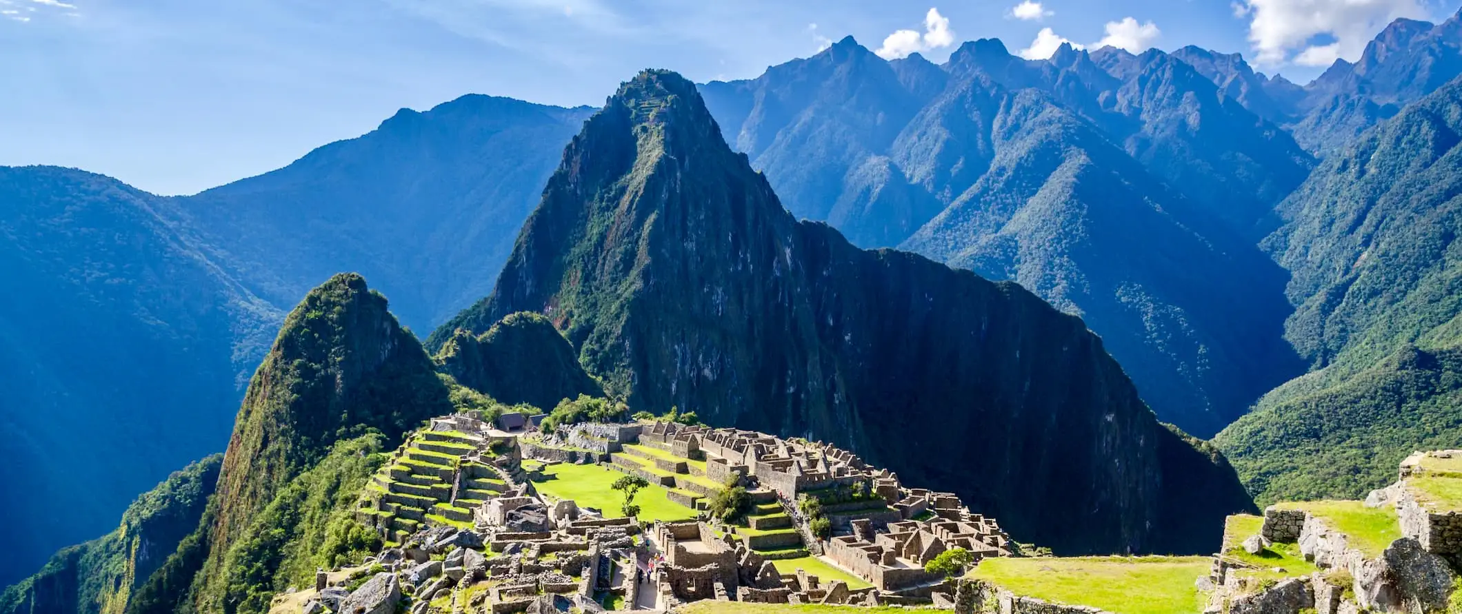 Machu Picchu, Peru mit sanften Bergen in der Ferne an einem hellen und sonnigen Tag