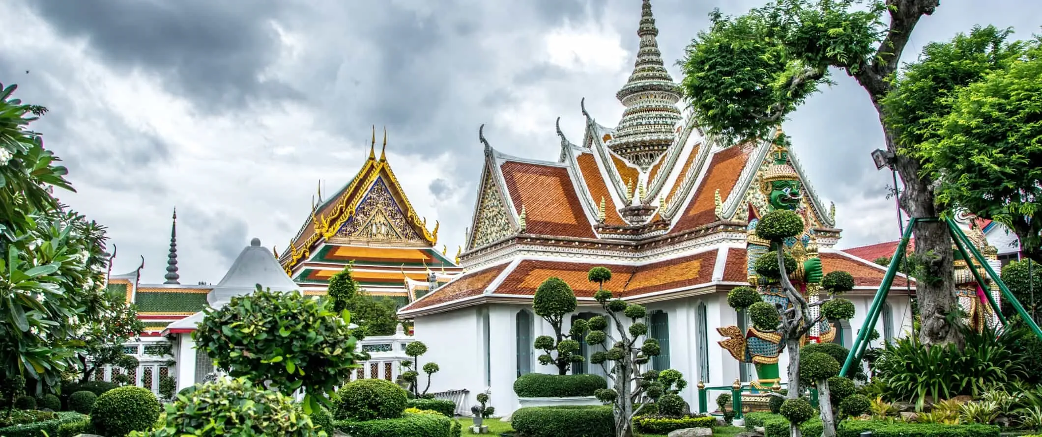 Aranyozott épületek a Wat Arun templomegyüttesben, ápolt topiáriummal körülvéve, Bangkokban, Thaiföldön