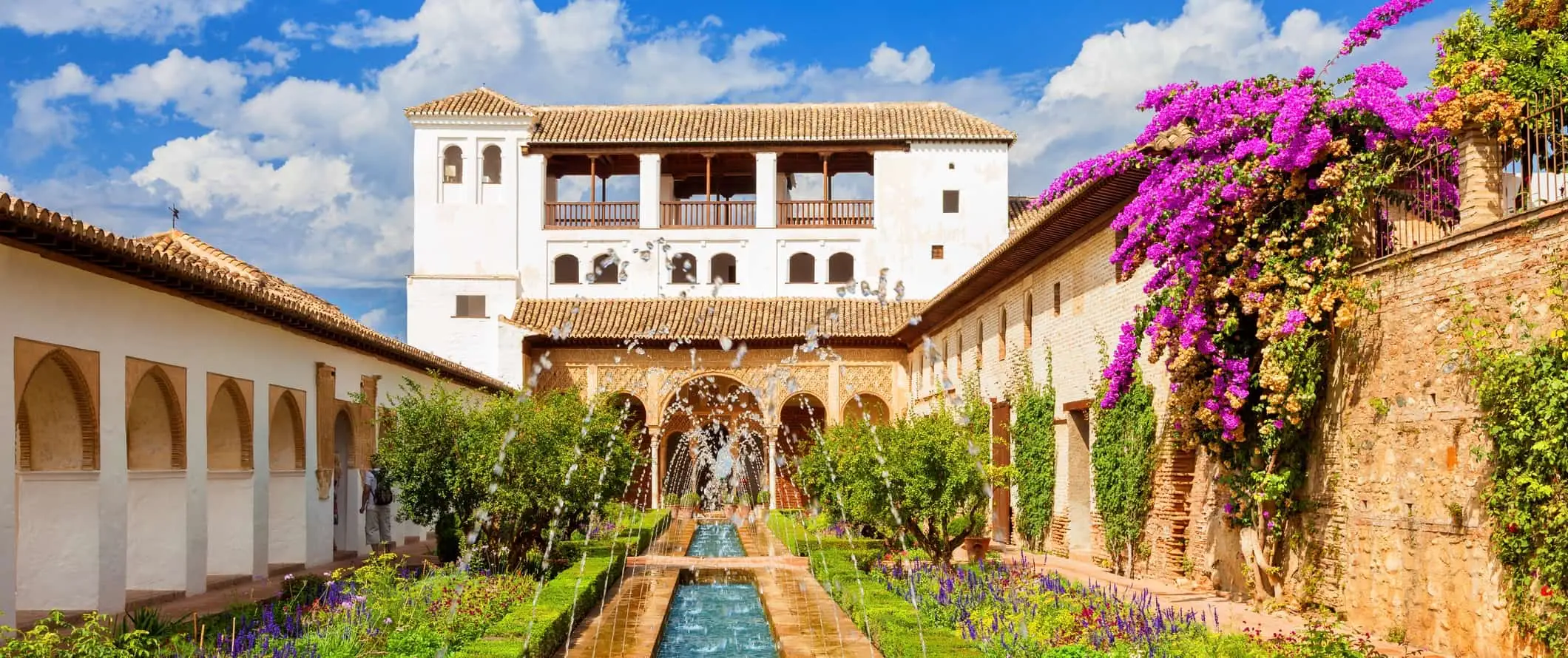 Het iconische Alhambra-paleis in Granada, Spanje, met een lange fontein en weelderig groen