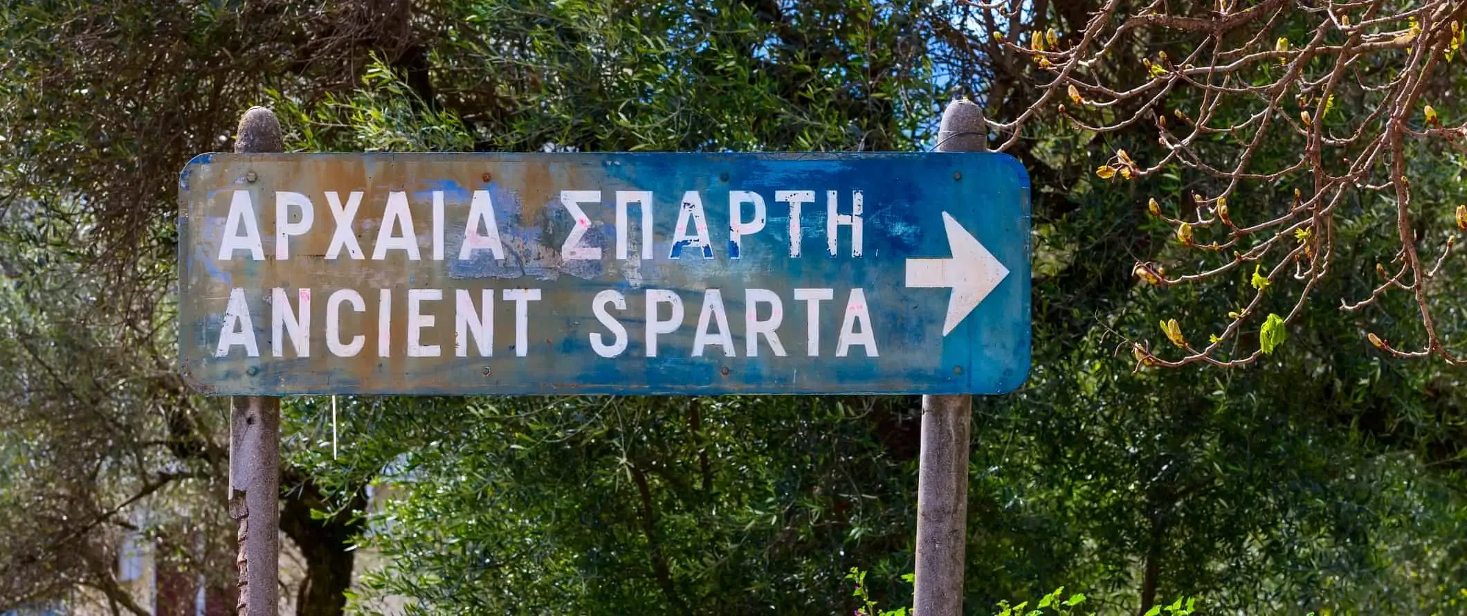 Papan tanda jalan biru menunjuk ke Sparta Purba di Greece.