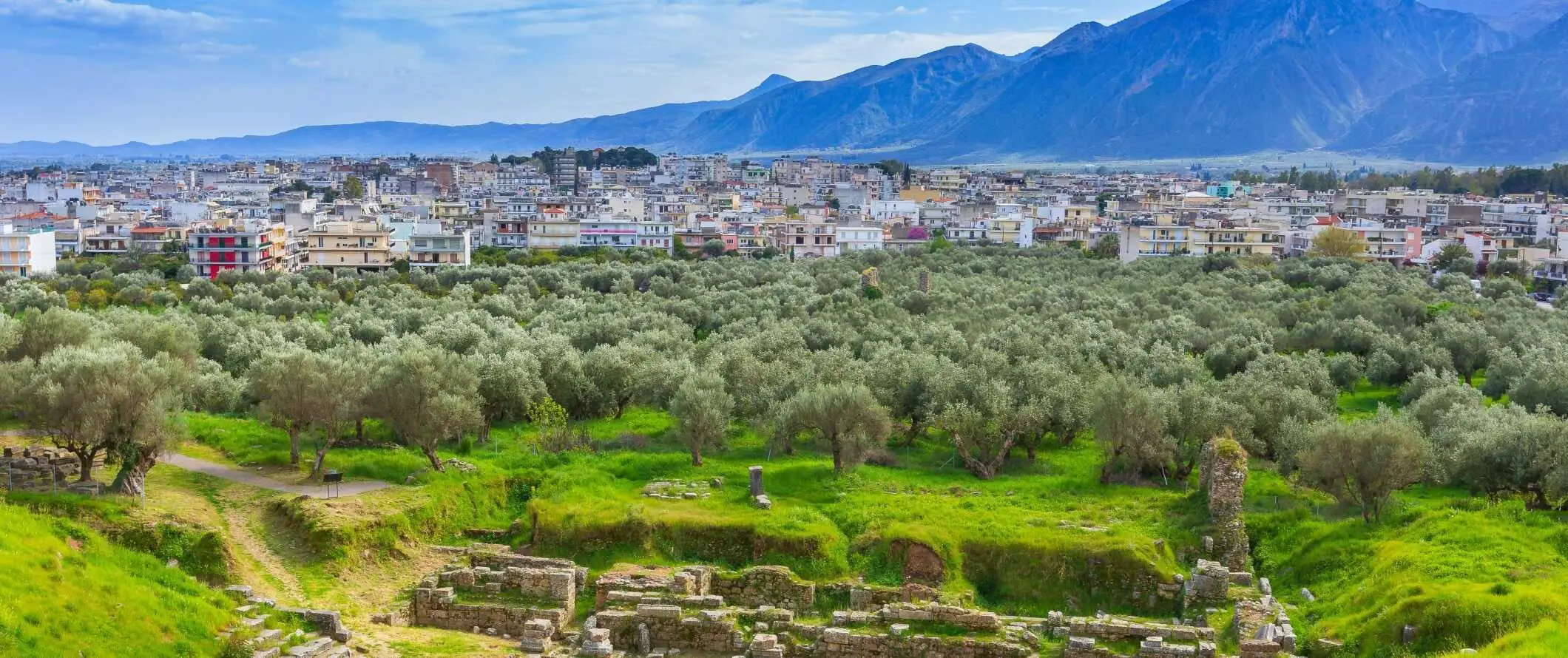 Gamle ruiner i forgrunnen med den moderne byen Sparta og fjell i bakgrunnen i Hellas