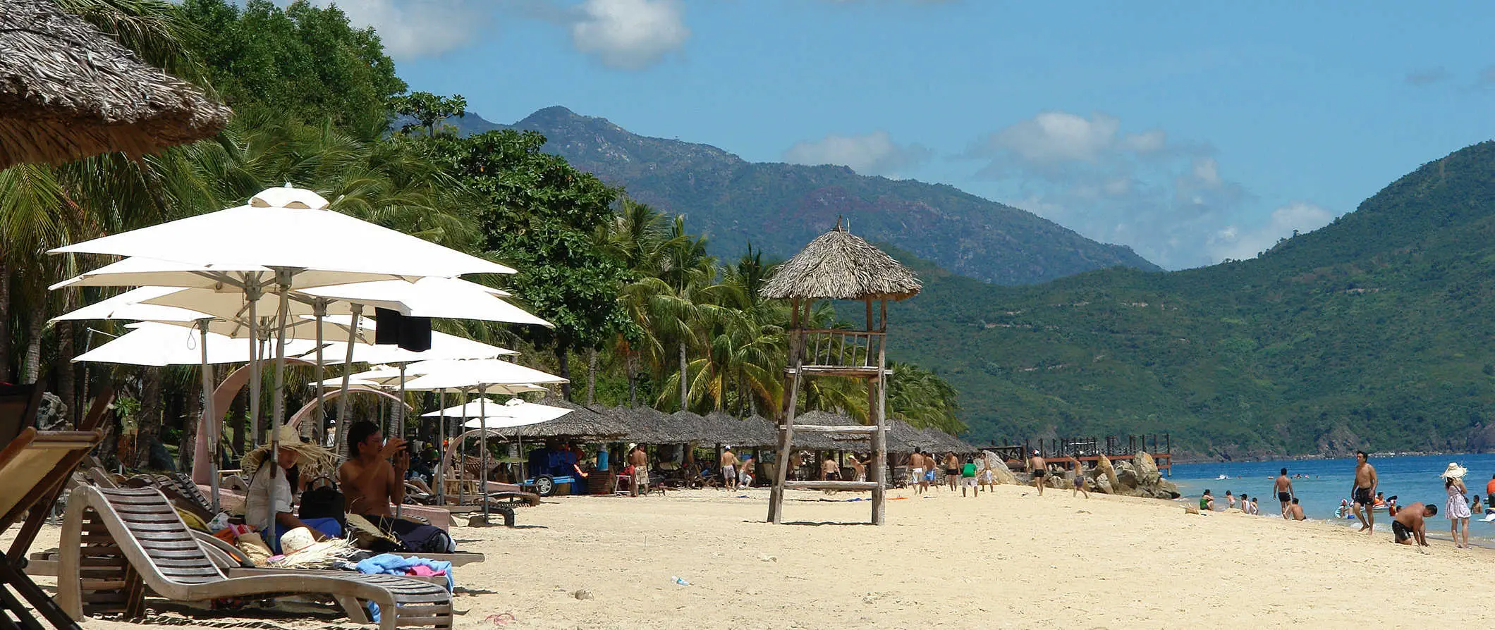 Het strandtafereel langs de jassen van Nha Trang, Vietnam, met de skyline van de stad hoog langs de kustlijn