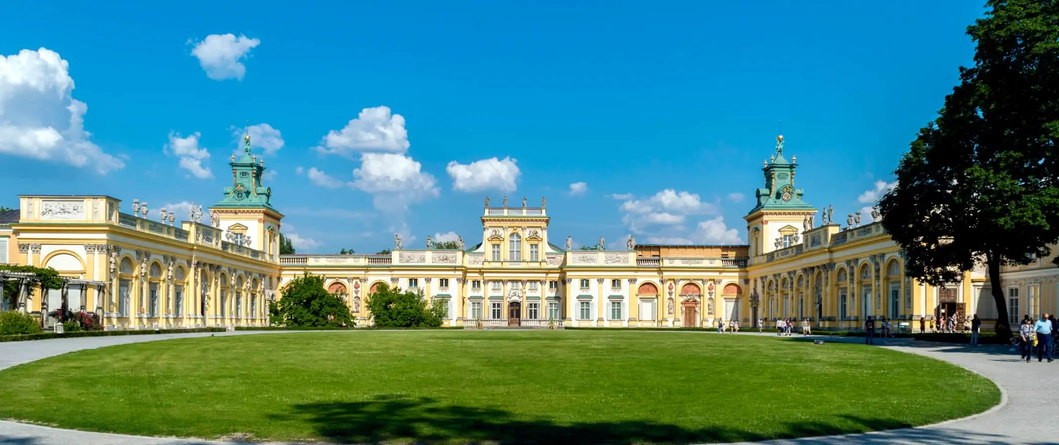 Široký, kráľovský palác obklopený zelenou trávou za slnečného dňa vo Varšave v Poľsku