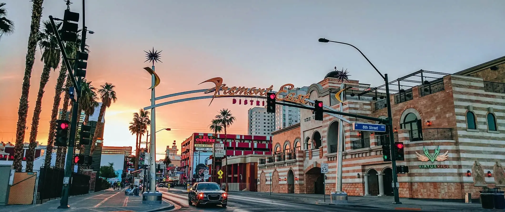 Insegna al neon che si estende su una strada fiancheggiata da palme al tramonto, dicendo