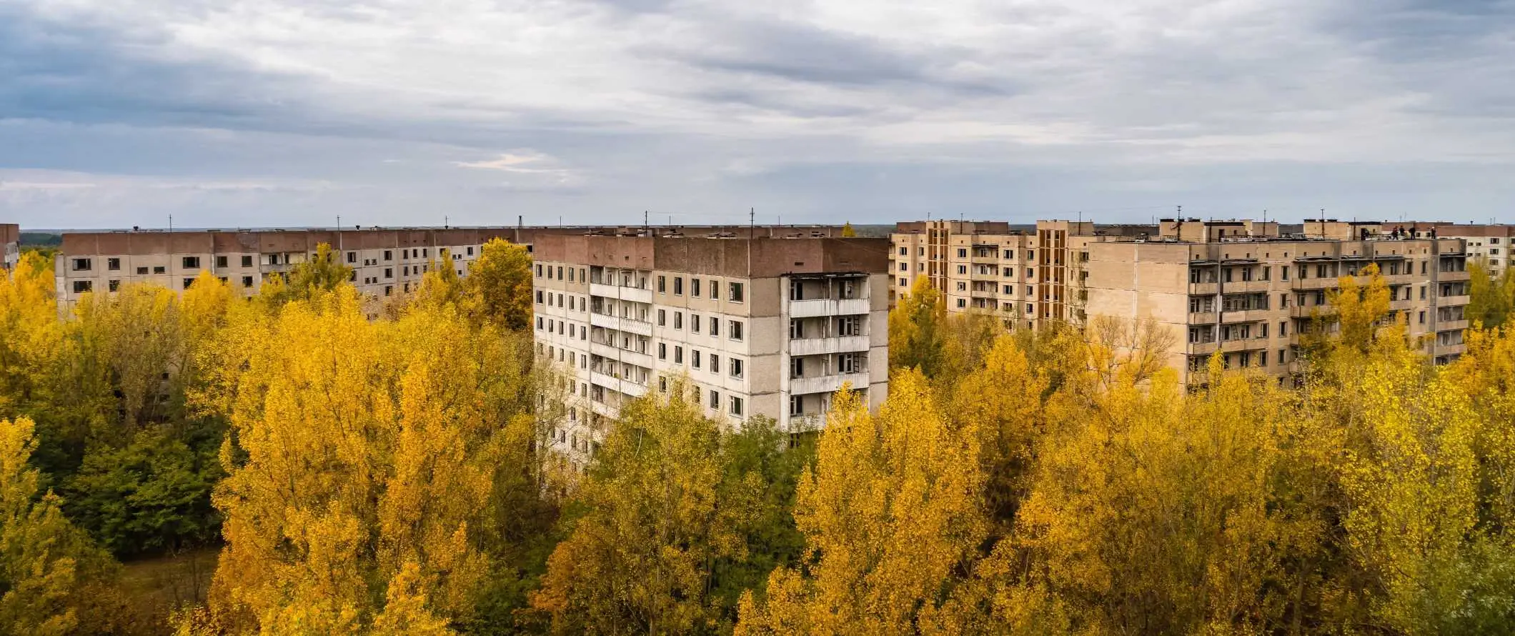 Pemandangan bangunan pangsapuri terbiar dengan pokok tumbuh di sekelilingnya di Chernobyl, Ukraine