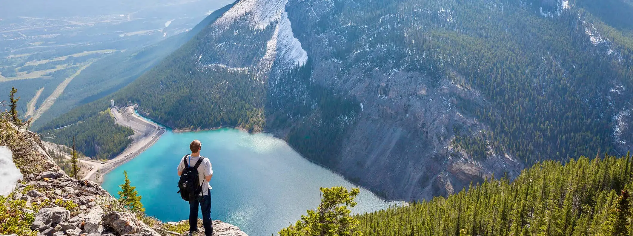 een solowandelaar die het uitzicht over de bergen van Canada bewondert met een meer in de verte