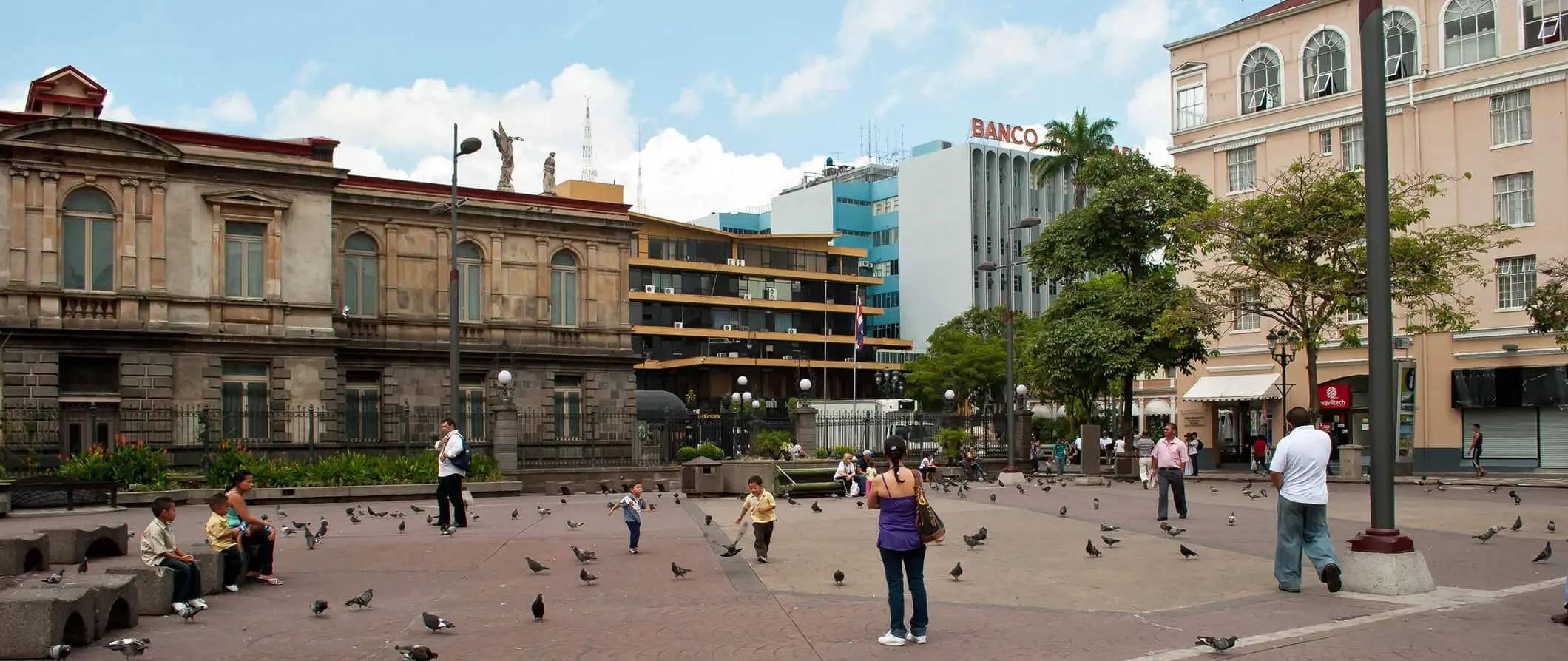 Folk som går rundt et sentralt torg fylt med duer i San Jose, Costa Rica