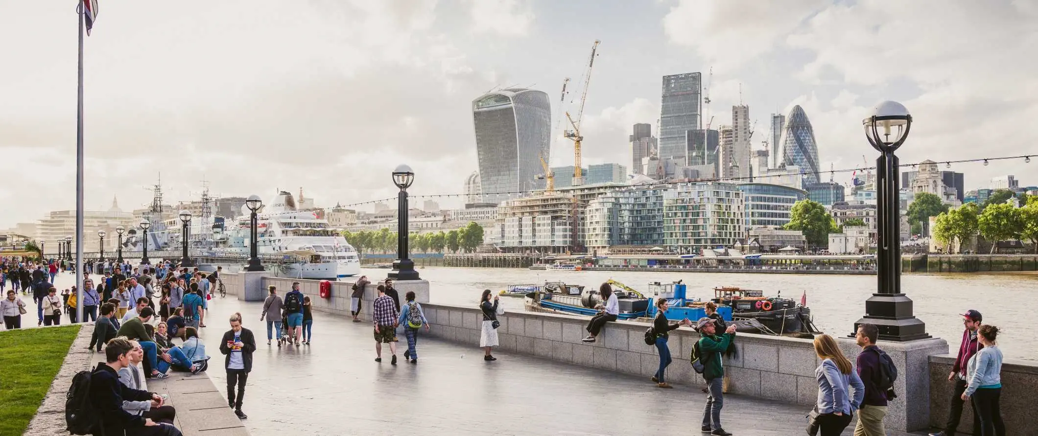 Folk som går rundt ved vannkanten av Themsen med London