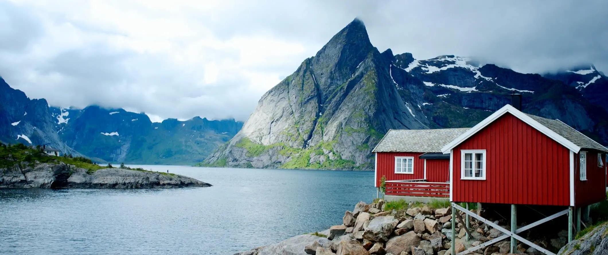 fiordes pitorescos na Noruega com uma cabana vermelha em primeiro plano ao longo da costa acidentada