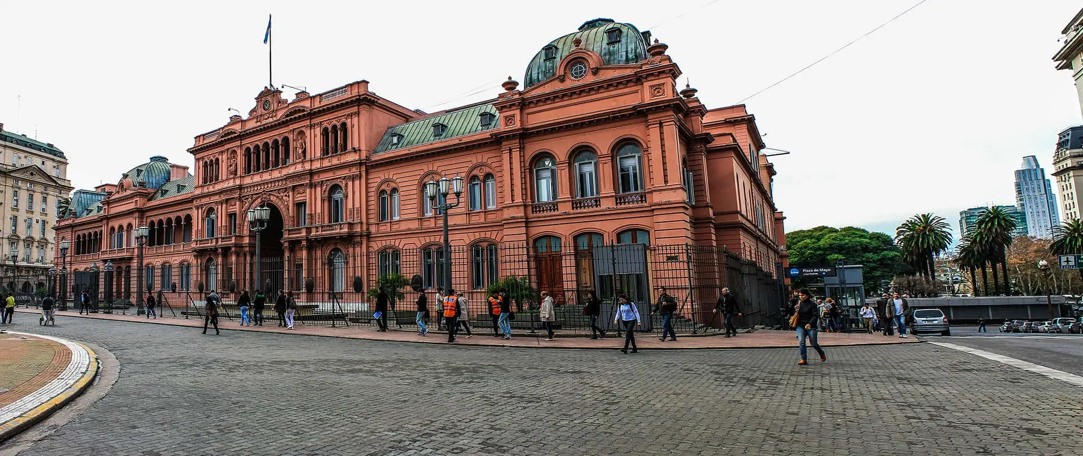 Vedere pe stradă din Buenos Aires, Argentina, cu oameni care se plimbă prin fața clădirii istorice Casa Rosada