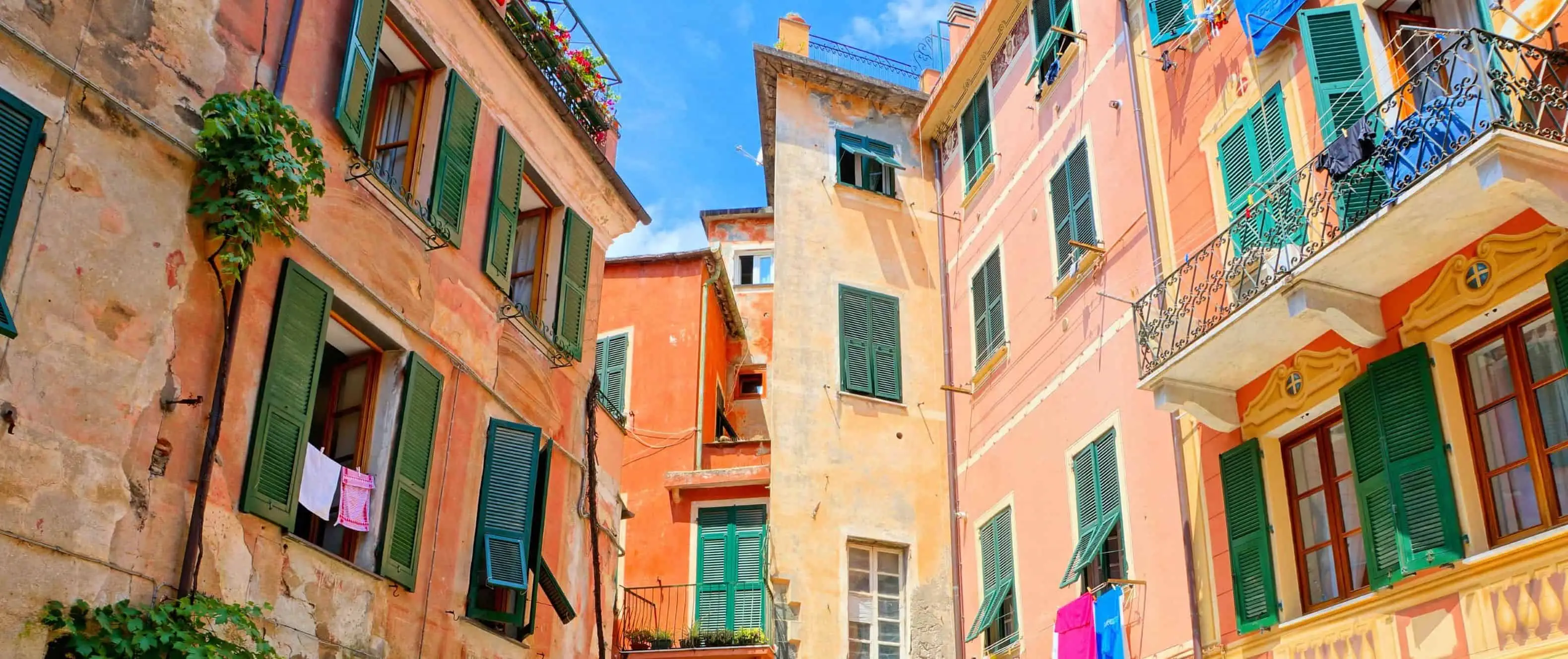 Edifici arancioni colorati e piccola piazza con un ristorante nelle Cinque Terre, Italia.