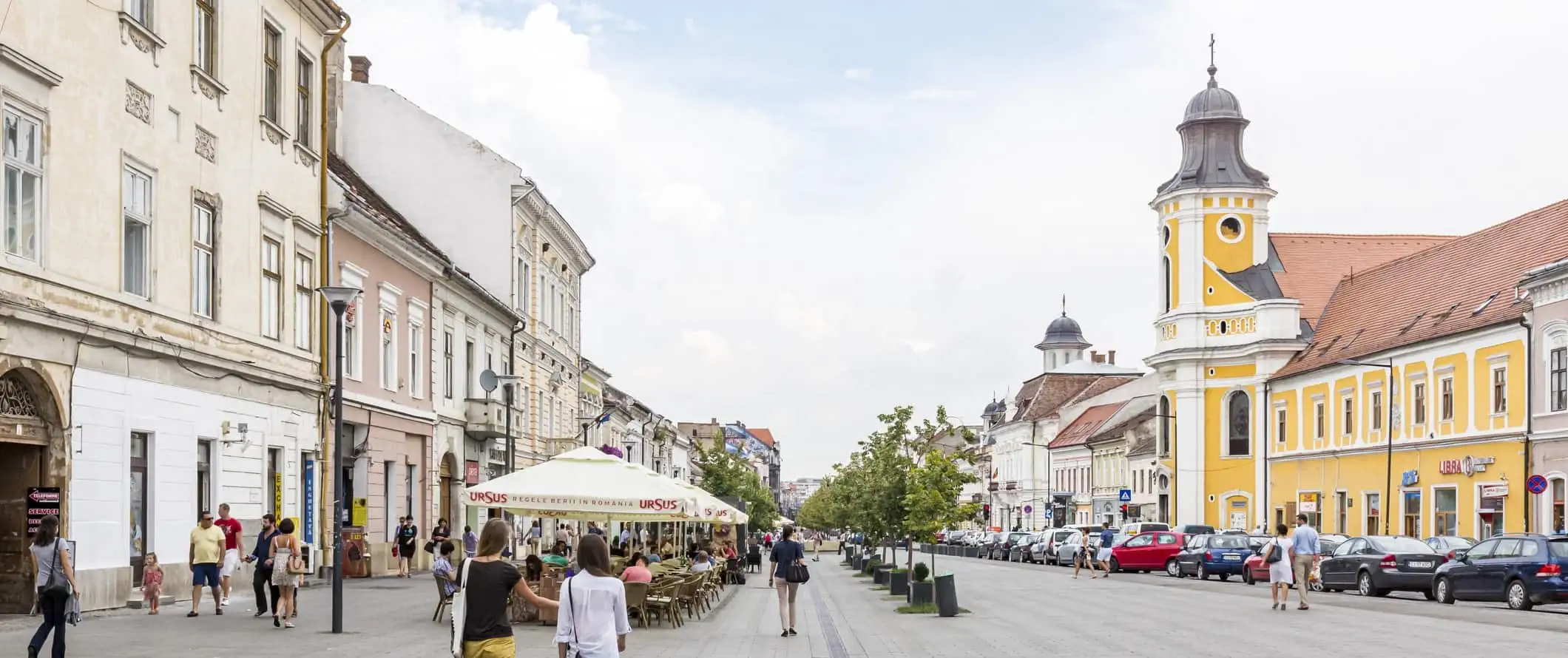 Gågate med restaurantterrasser og pastellfargede bygninger i byen Cluj-Napoca, Romania